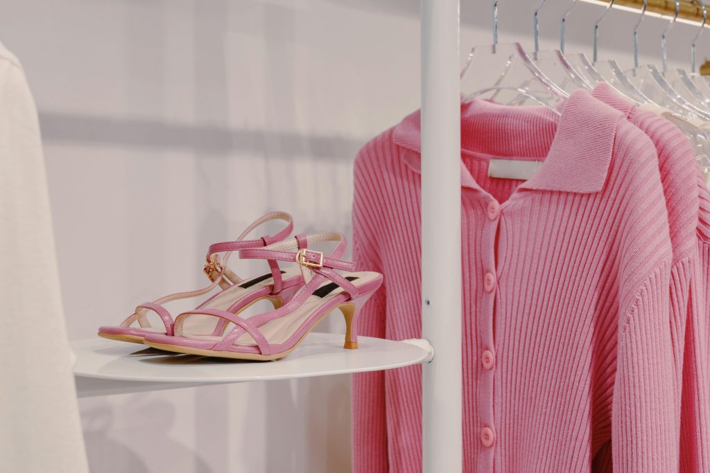 Sandales roses et pull en maille en vitrine de boutique mode.